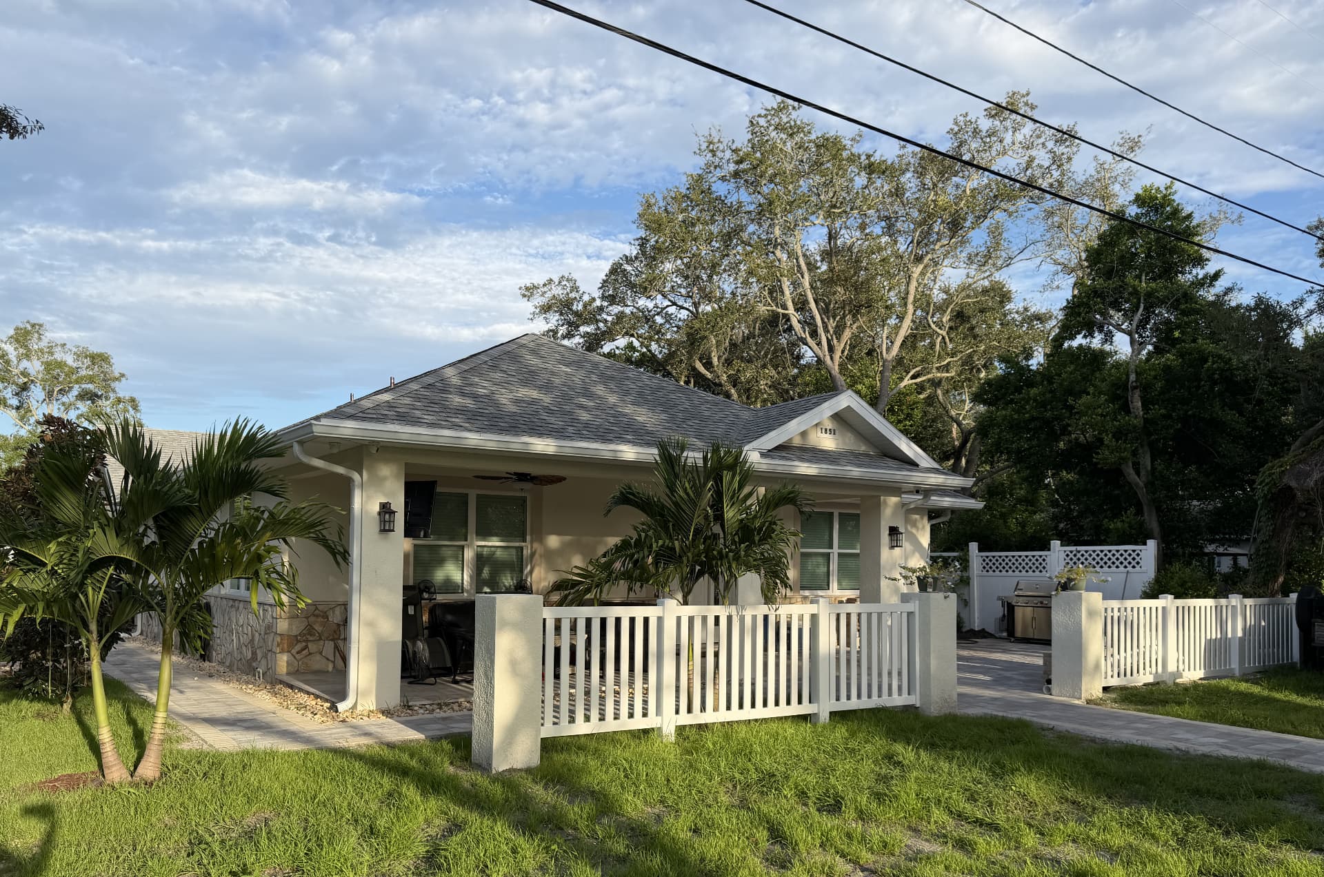 Finished Tarpon Springs custom home with a covered porch, palm landscaping, and white fence